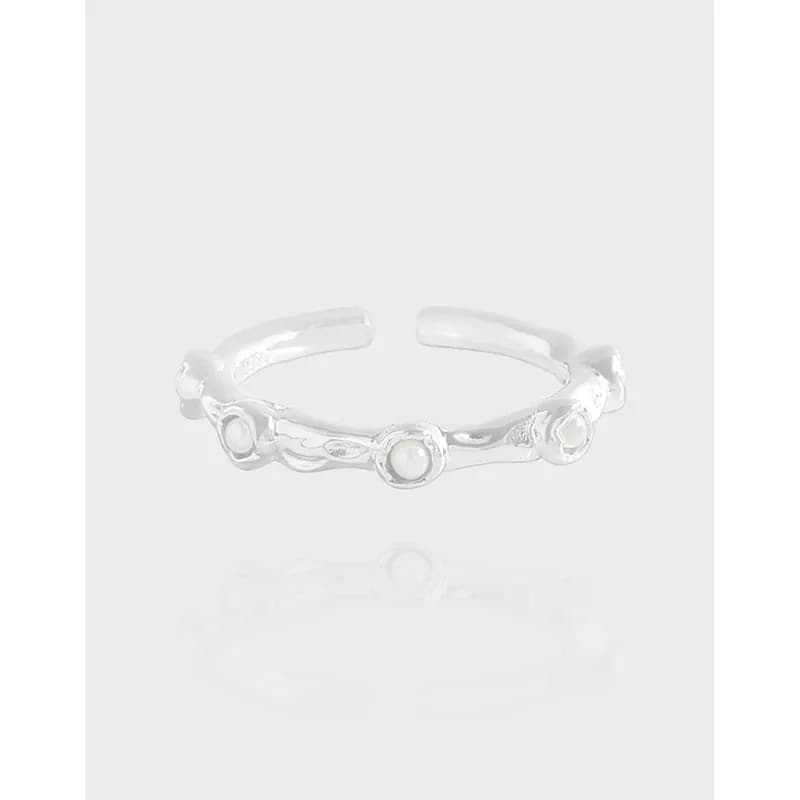 Open sterling silver ring with bezel-set pearls along a wavy band.