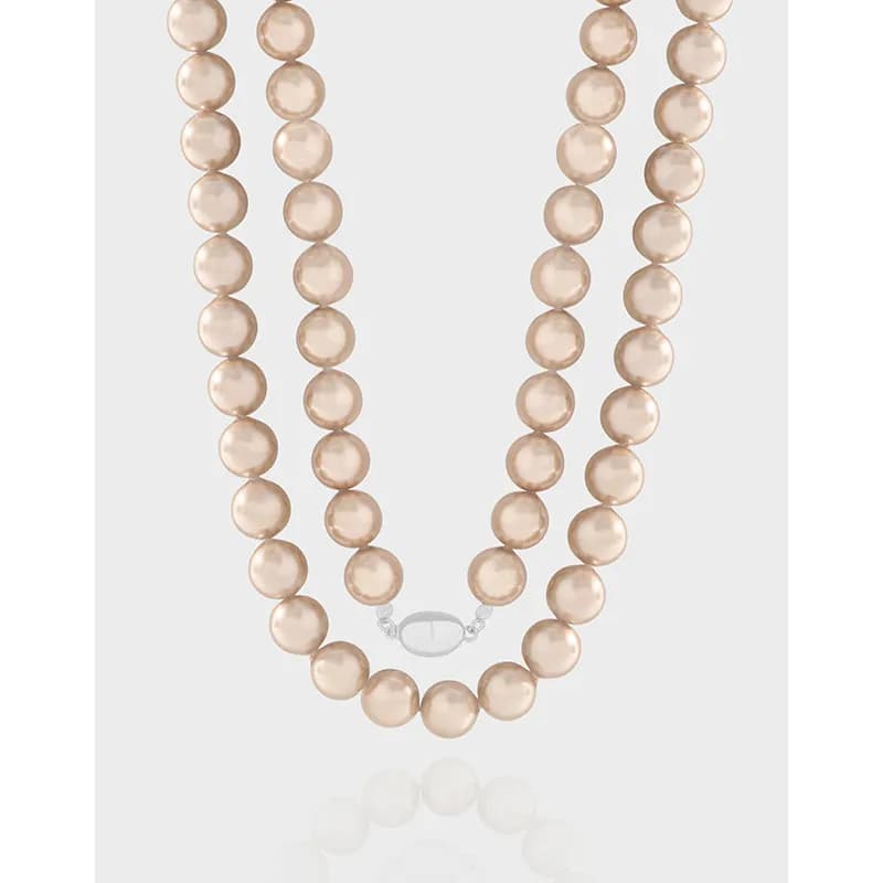 Two-strand blush pink pearl bead necklace with a polished silver clasp on a light background.