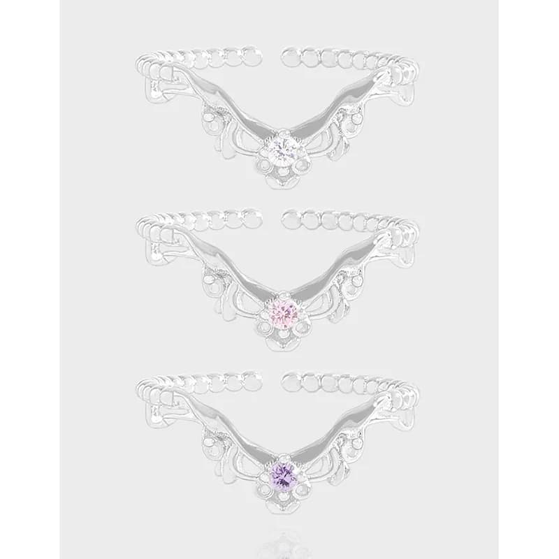 Polished sterling silver ring with winged centerpiece and small central crystal on a light background.