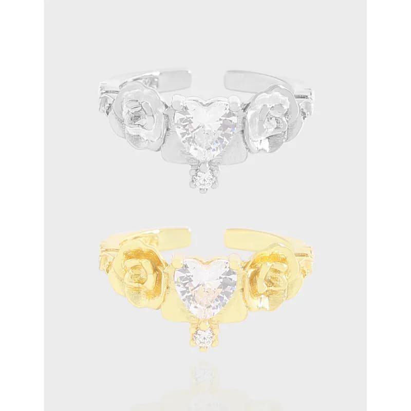 Two-tone rings with a heart-shaped crystal centerpiece and rose side motifs in silver and gold finishes.