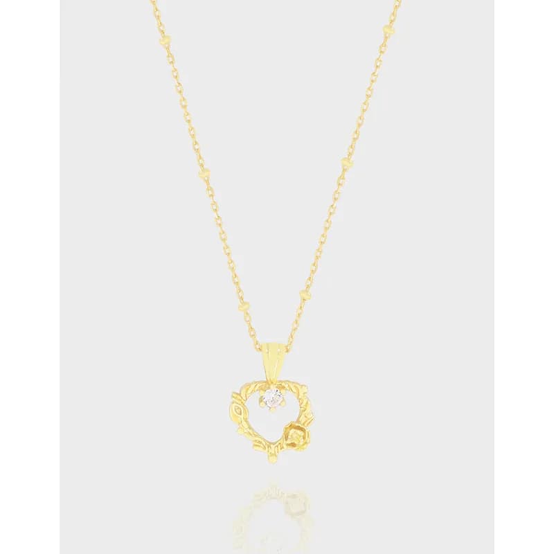 Gold-toned leaf-wreath pendant necklace with a central stone on a delicate chain.