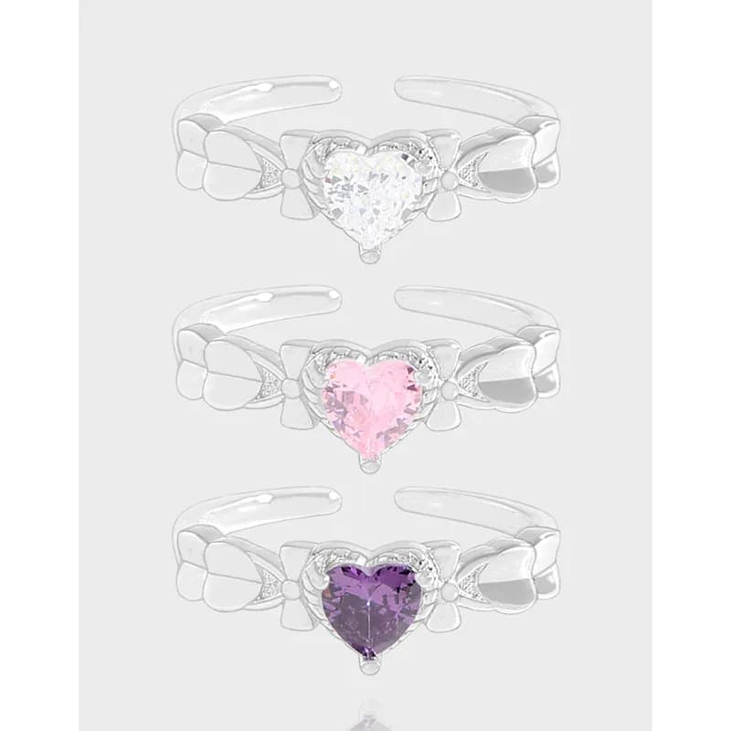 Polished sterling silver ring with a heart-shaped centerpiece and bow motifs on either side.
