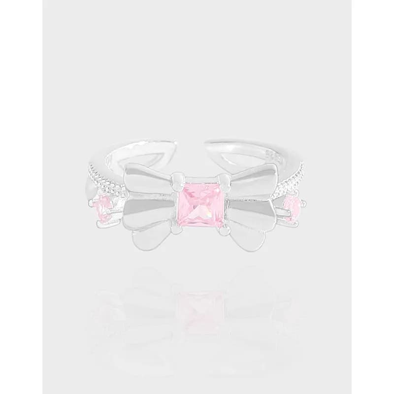 Polished sterling silver ring with a square pink centerpiece and bow accents, front view.