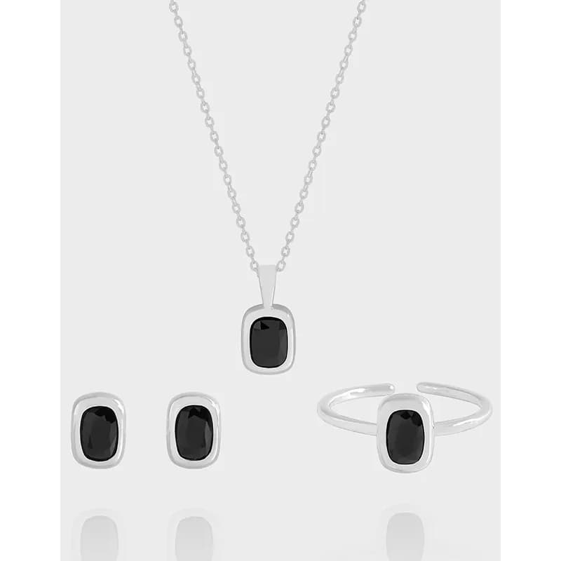 Polished sterling silver bezel-set black stone earrings displayed alongside a matching necklace and ring.