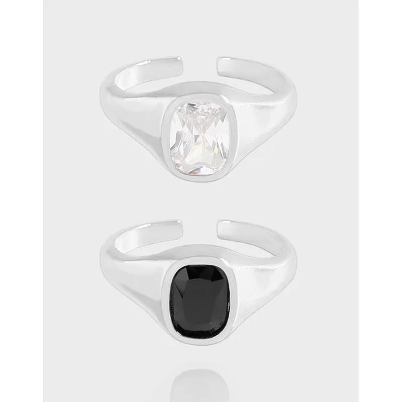 Two polished sterling silver rings with bezel-set stones, one clear and one dark, shown in an open-band design.