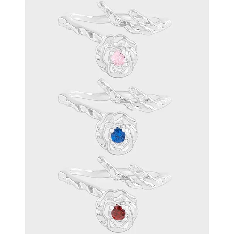 Polished sterling silver floral ring with a colorful gemstone center visible on a slim, twisted band.