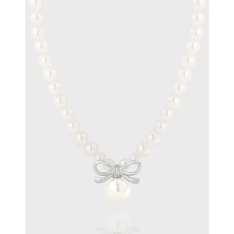 Pearl strand necklace with a silver bow pendant and single hanging pearl in the center.