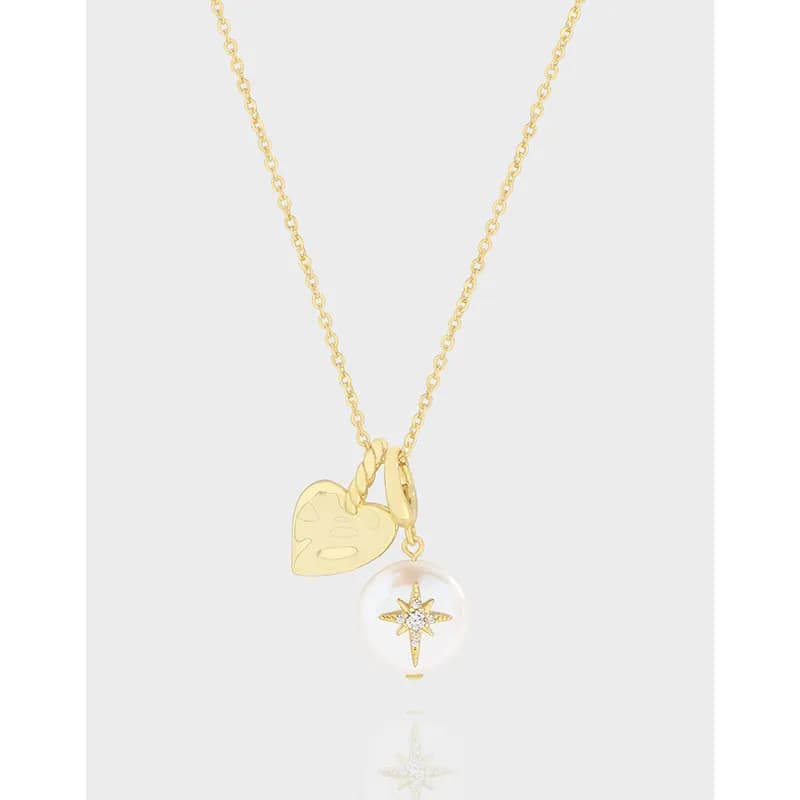 A sterling silver necklace with a heart enamel charm and a glass globe pendant containing a starburst design
