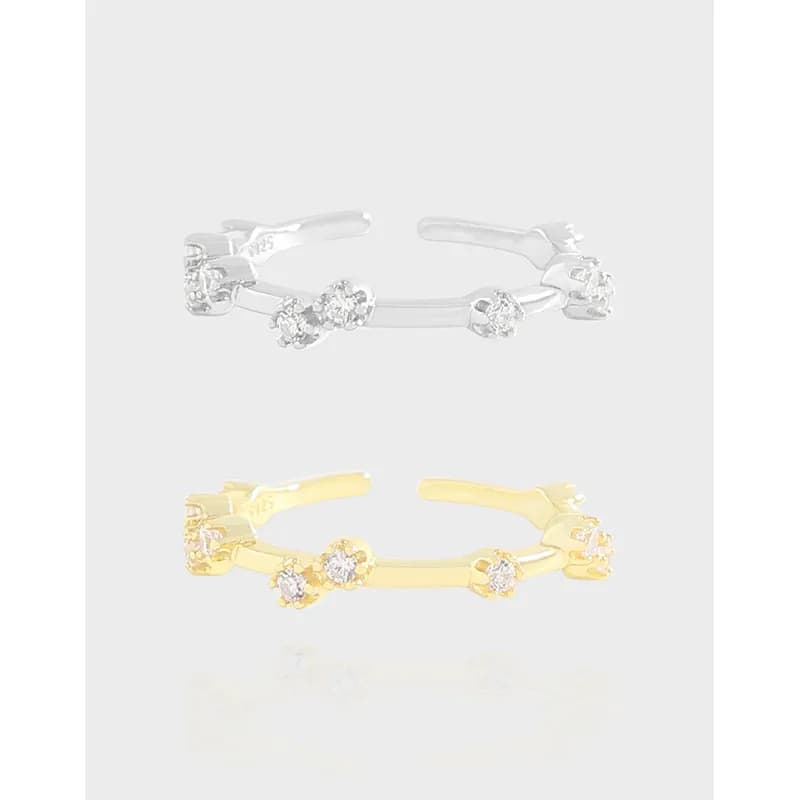 Polished sterling silver ring with three stone clusters on a curved open band.