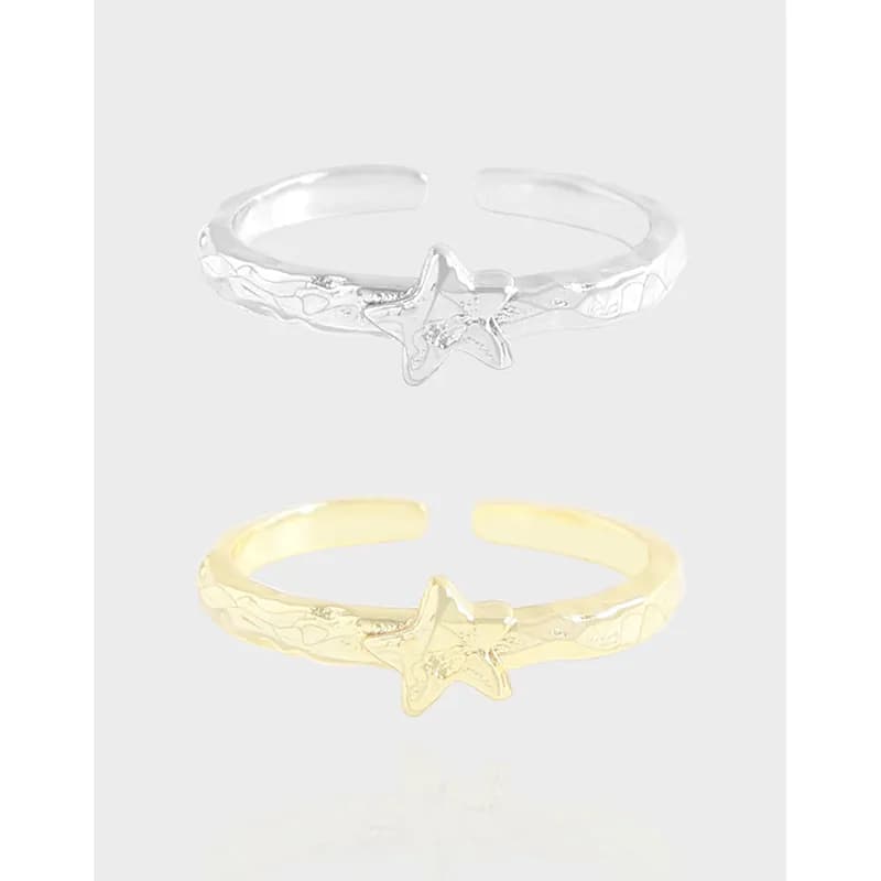 Polished sterling silver open-band ring with a star centerpiece and textured pattern on the band, shown in two tones against a light background.