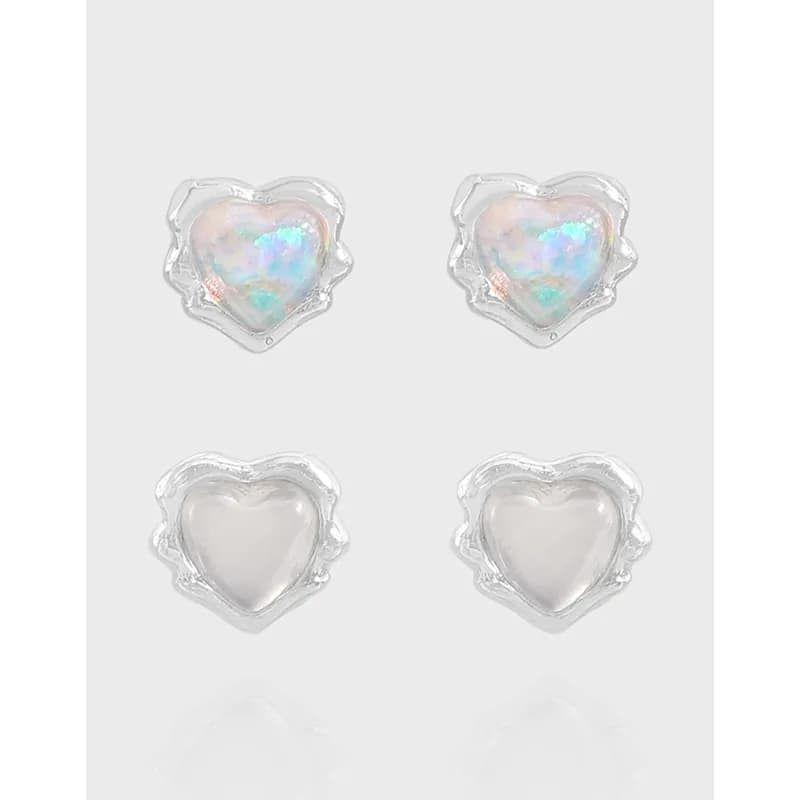 Silver heart-shaped stud earrings with opal-like centers and scalloped edges on a light gray background.