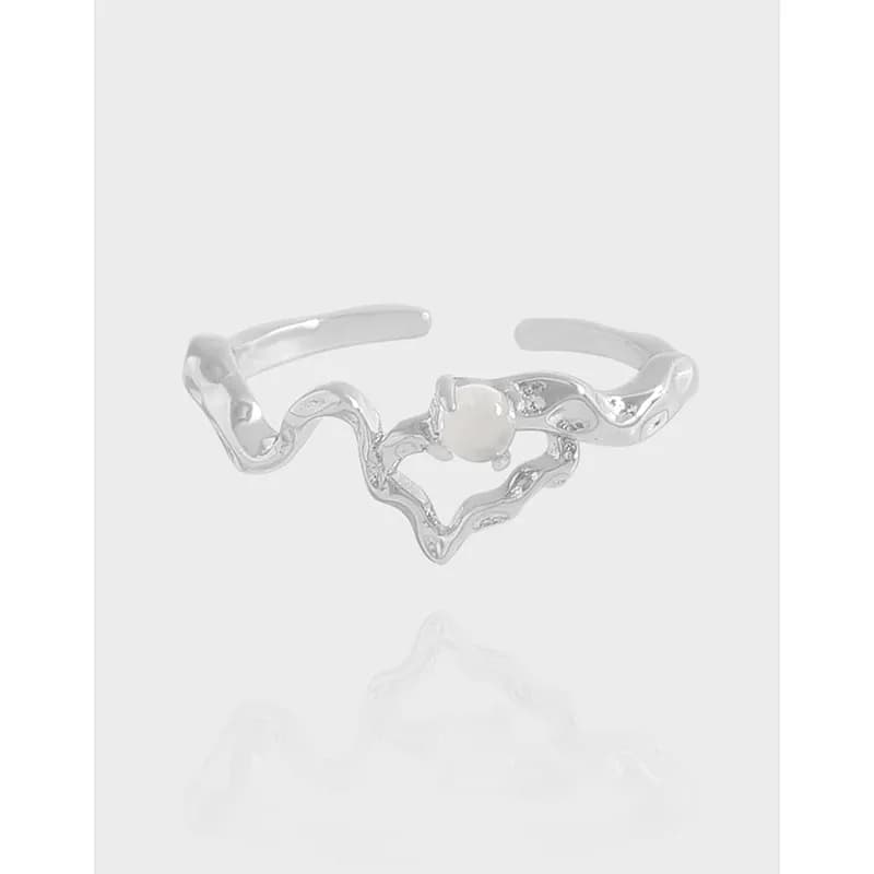 Polished sterling silver ring with a wavy heart motif and small stones on the band.