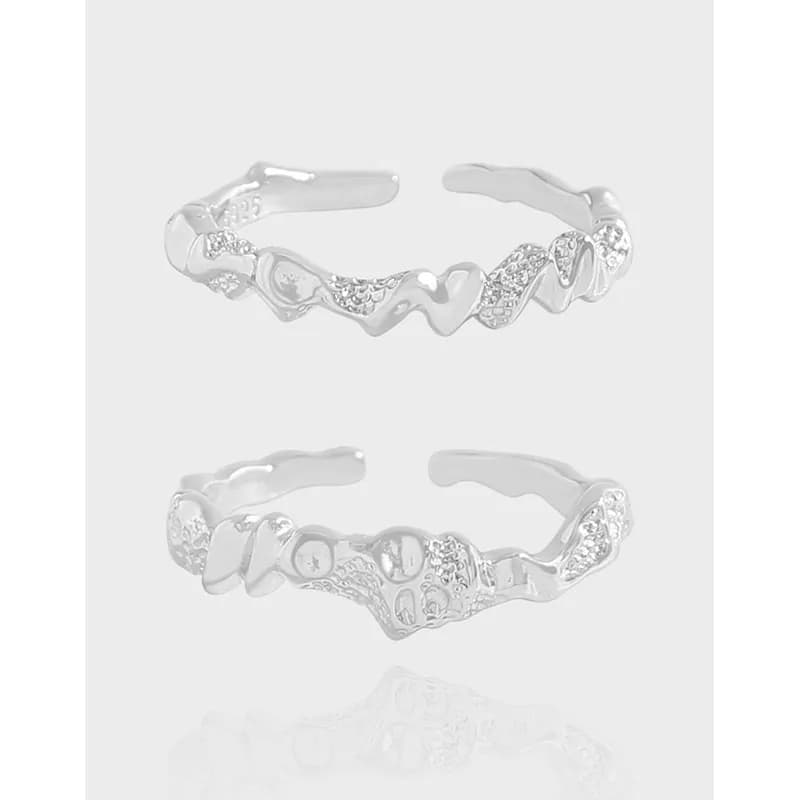 Polished sterling silver ring with a flowing, wavy band and pavé accents shown from two angles.