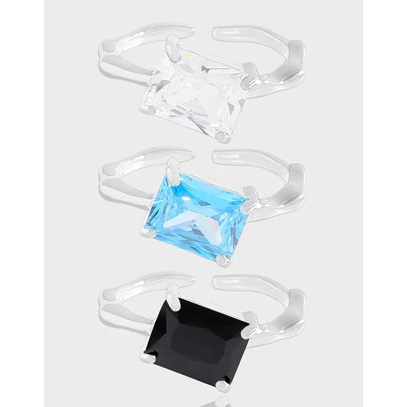 Three square-cut gemstone rings in sterling silver with four-prong settings in white, blue, and black stones.