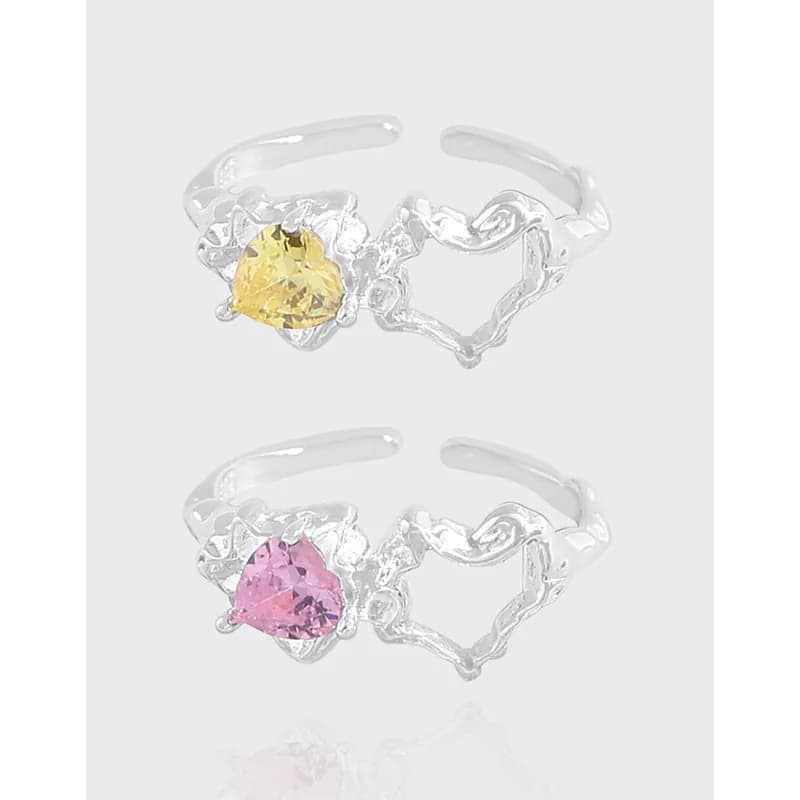 Two sterling silver open rings with heart-shaped band details and pear-cut stones in yellow and pink.