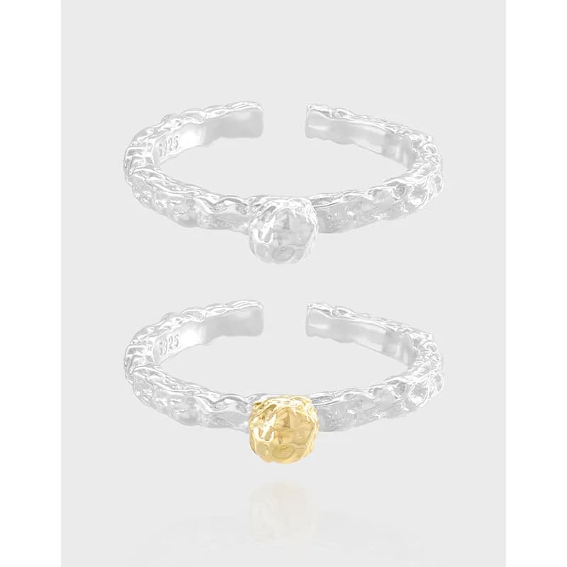 Two sterling silver rings with a textured twisted band and a single raised ball bead, one plain silver and one with a gold-tone ball.