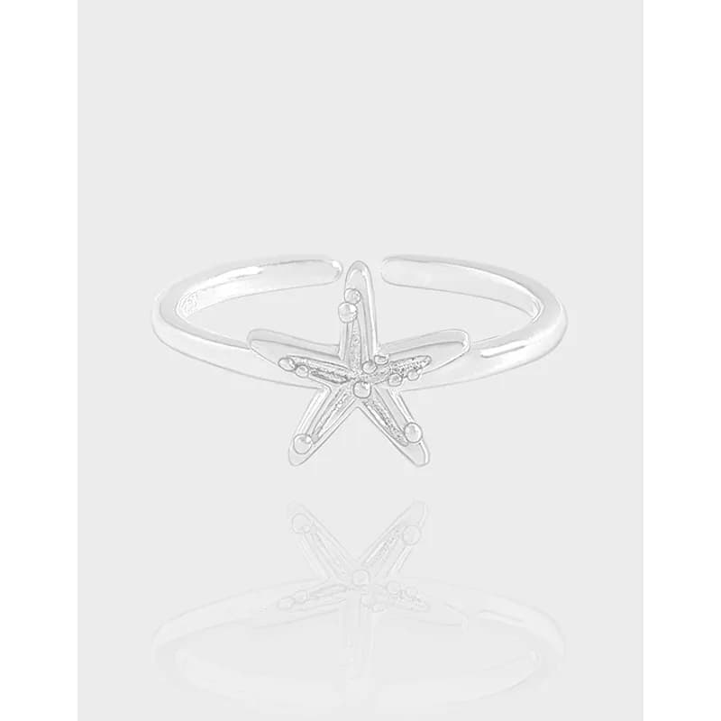 Polished sterling silver starfish ring displayed on a light background.