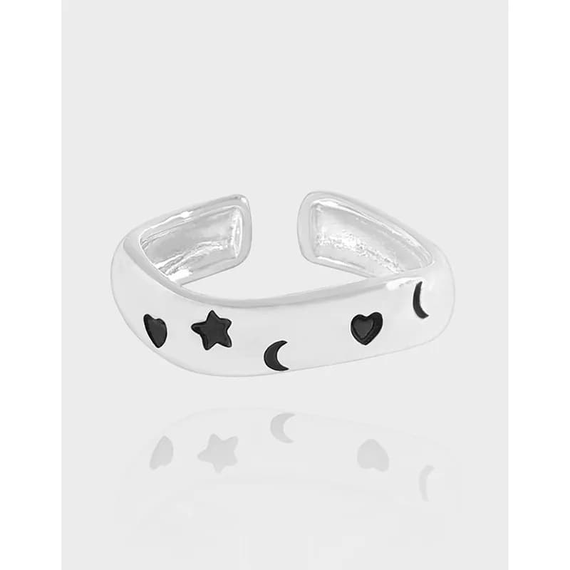 Open sterling silver ring with star, heart, and crescent moon cutouts on a polished band.