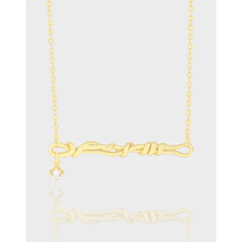 Polished knot-bar pendant necklace on a delicate chain with a small crystal drop.