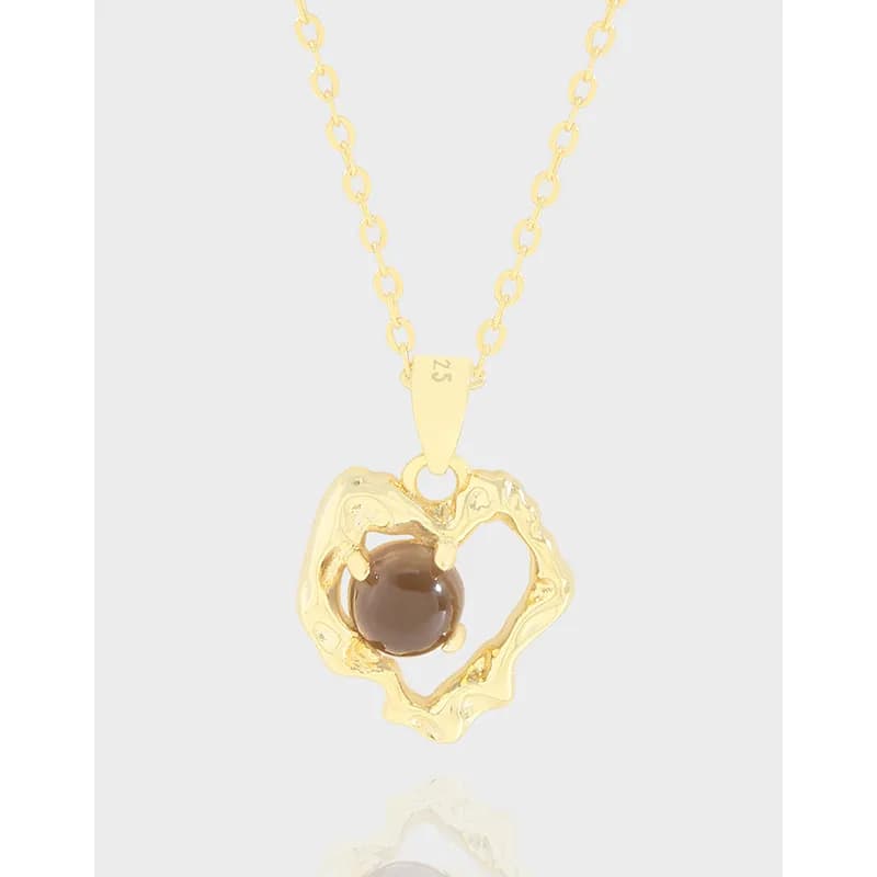 Polished silver heart pendant with an open frame and brown bead on a fine chain.