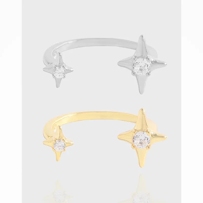 Polished sterling silver open ring with starburst ends and central stones displayed on white background