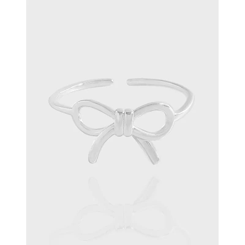 Polished sterling silver bow knot ring on a light gray background.