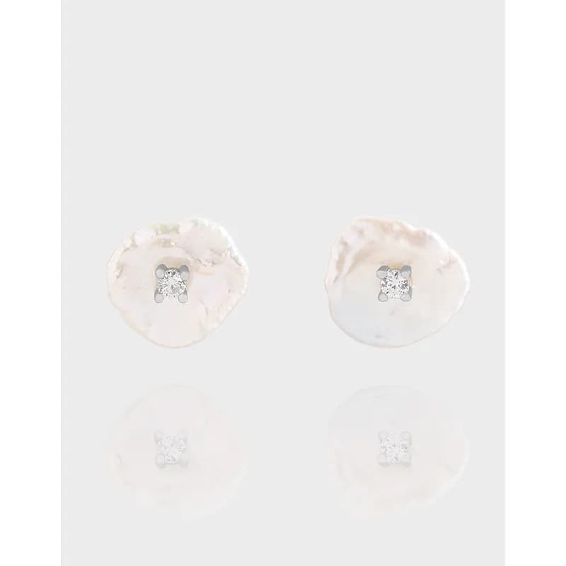 Two irregular, shell-like silver discs with small central stones as stud earrings.