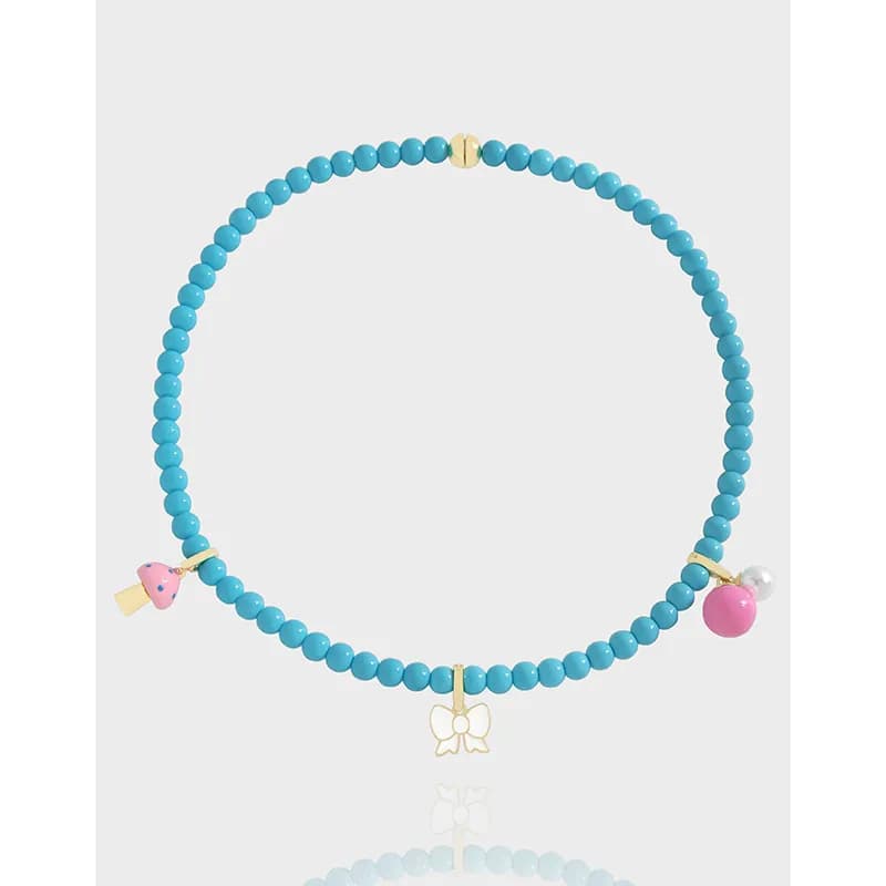 Turquoise beaded necklace with gold-tone charms including a bow and decorative pendants.