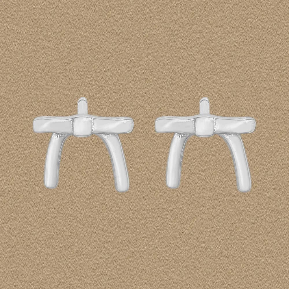 Pair of polished sterling silver bow-bar stud earrings with curved stems on a sandy background.