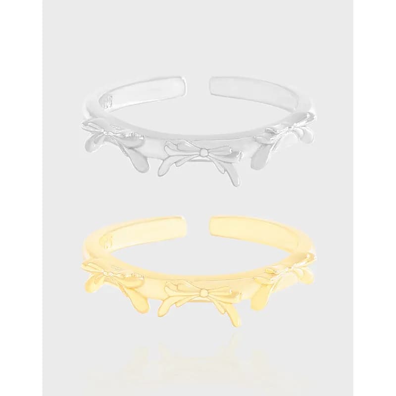 Polished sterling silver ring with floral daisy motifs along a slim open band, shown in silver and gold-tone variants.