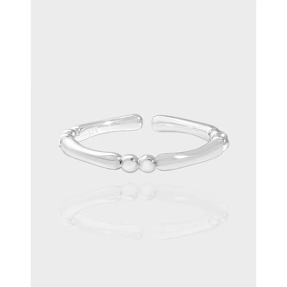 Polished sterling silver open ring with two central beads shown on a light background.