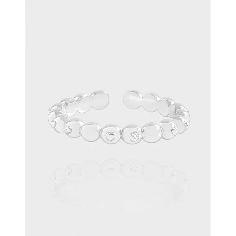 Open-band sterling silver ring with connected circular discs and heart cutouts on a white background.
