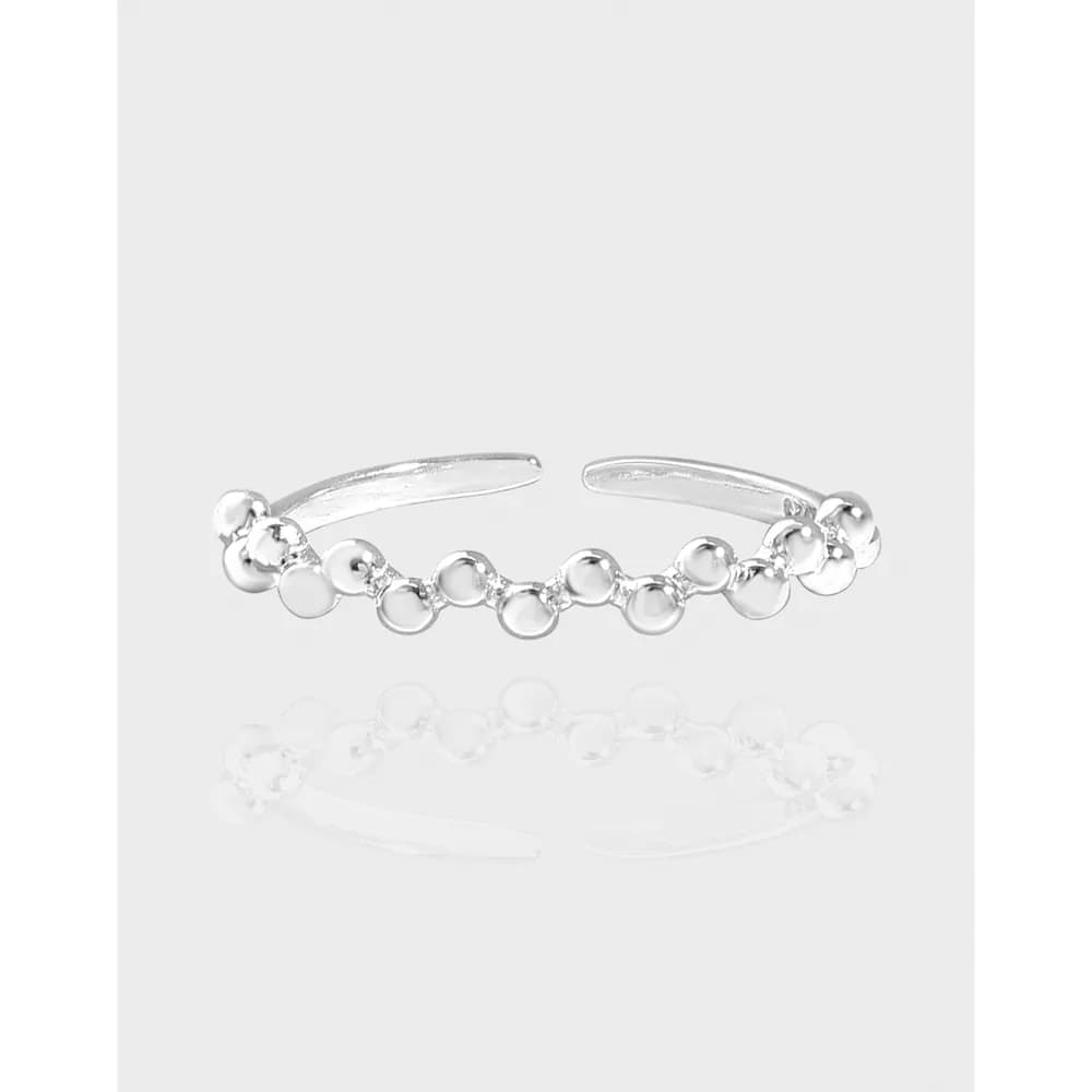Open sterling silver ring featuring a line of connected circular discs on the front.