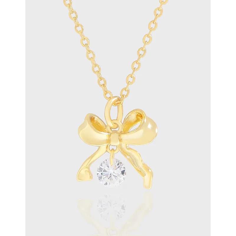Polished gold-tone bow pendant with crystal drop on a delicate chain