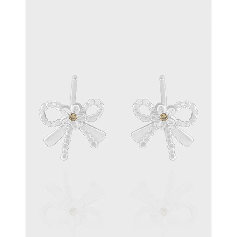 Pair of polished silver bow-shaped earrings with beaded loops and small central gemstone