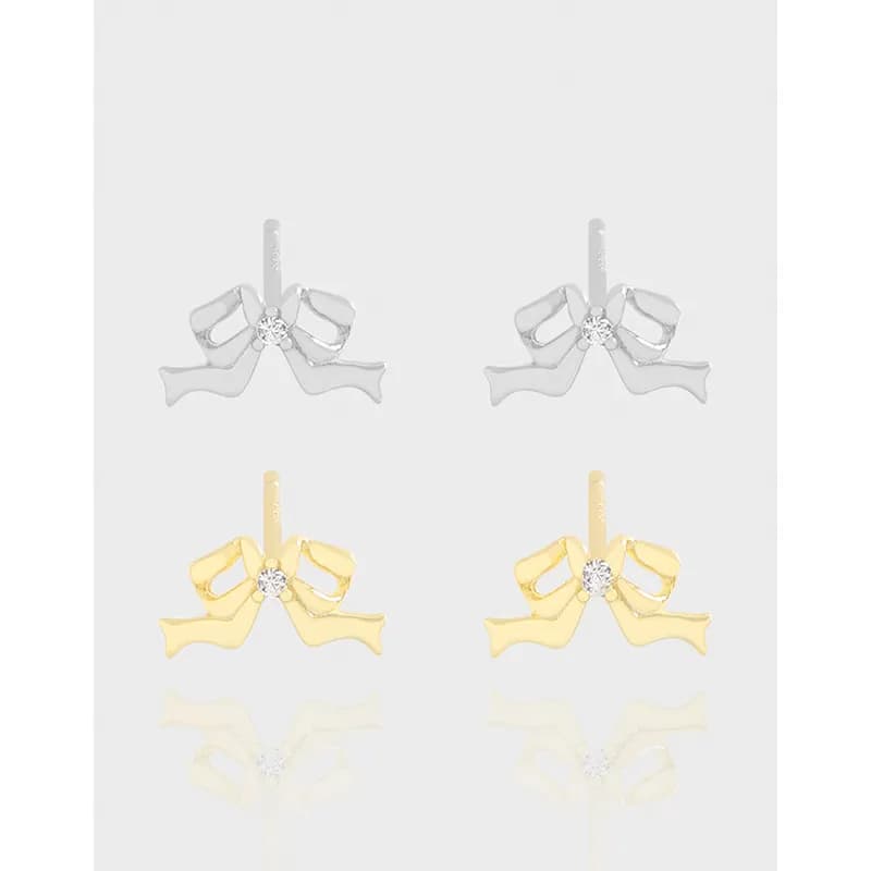 Silver and gold bow-shaped stud earrings with a small central gemstone, shown from the front