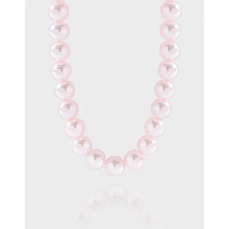 Close-up of a pink pearl bead necklace on a light background.