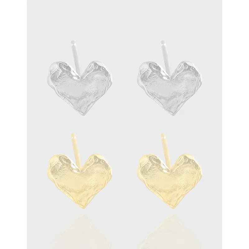 Pair of hammered heart stud earrings in silver and gold-tone finishes on a light background.