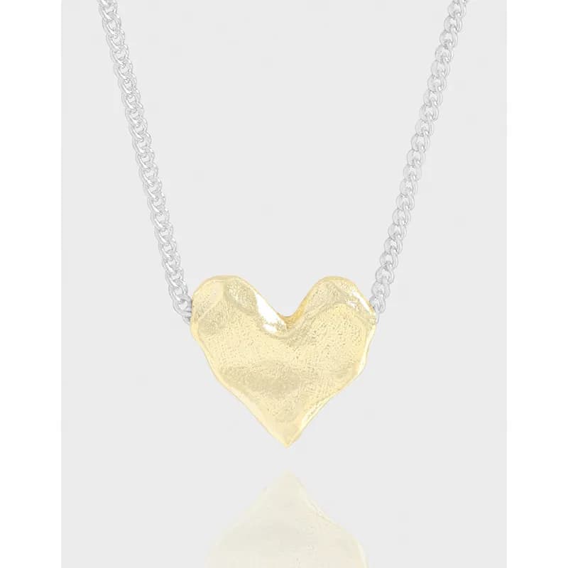Close-up of a two-tone heart-shaped pendant on a silver chain with a polished finish.