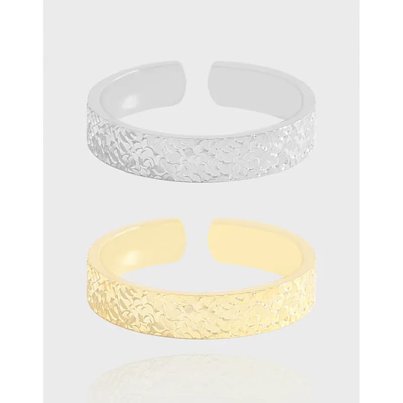 Open-ended textured band rings in silver and gold finishes shown on a light background.