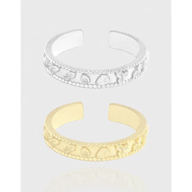 Polished open-ring in silver with shell and leaf motifs and beaded edging, shown beside a gold-tone version.