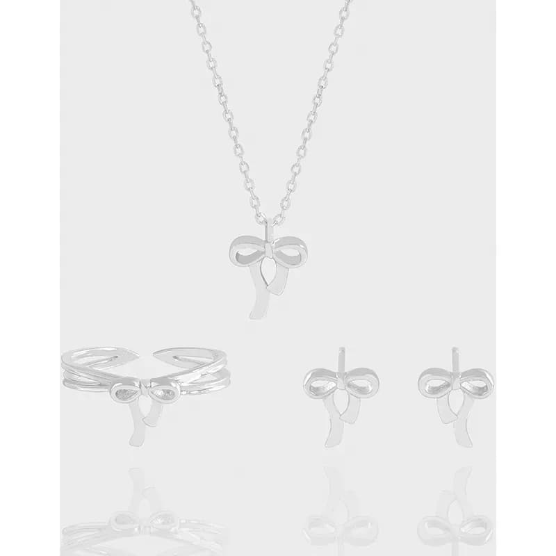 Polished sterling silver bow earrings with a matching bow pendant on a chain and rings displayed