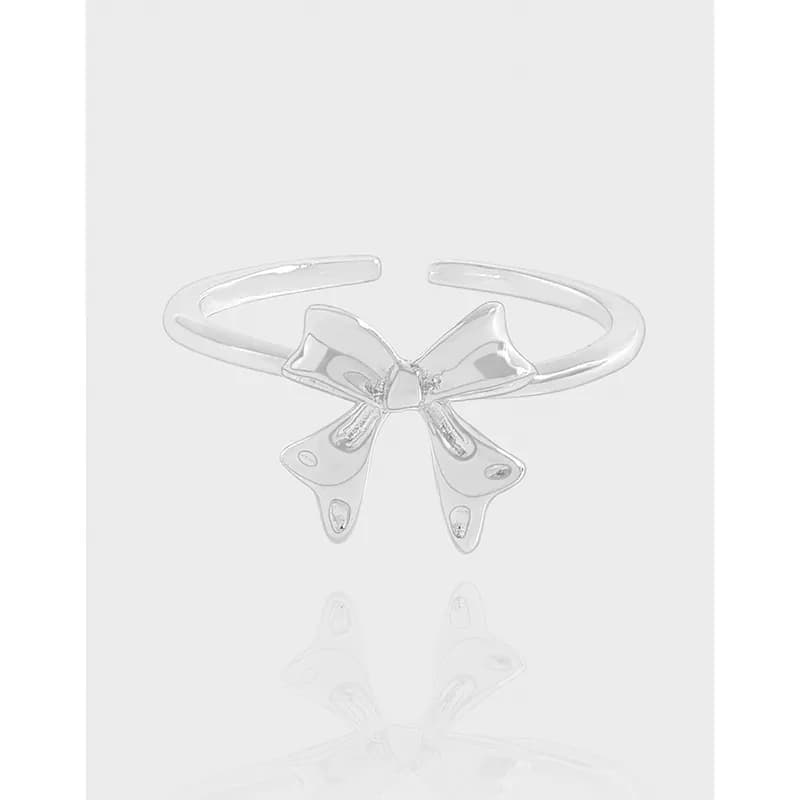 Polished sterling silver ring with a sculpted bow centerpiece on a light background.
