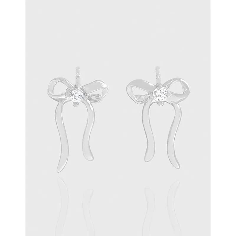 Polished sterling silver bow-shaped drop earrings with crystal centers and curved ribbon-like dangles.