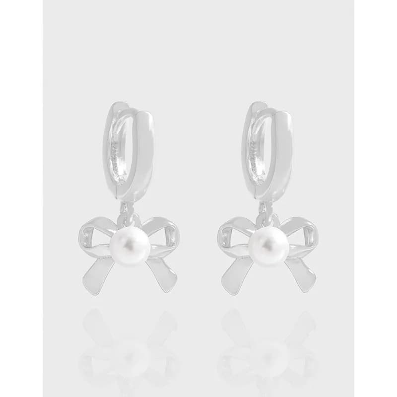 Polished sterling silver bow earrings with a central pearl hanging from small hoops