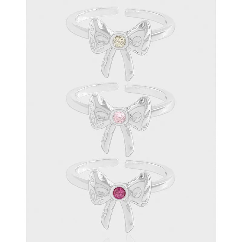 Sterling silver bow ring with enamel center on a light backdrop, shown in a vertical stack of three.