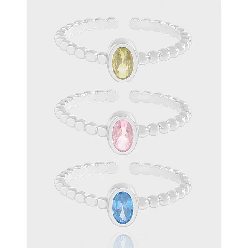 Three sterling silver oval bezel rings with beaded bands and colored gemstones shown in a stacked arrangement.