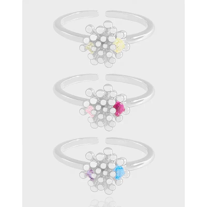 Silver daisy floral ring with enamel petals on an open-band setting.