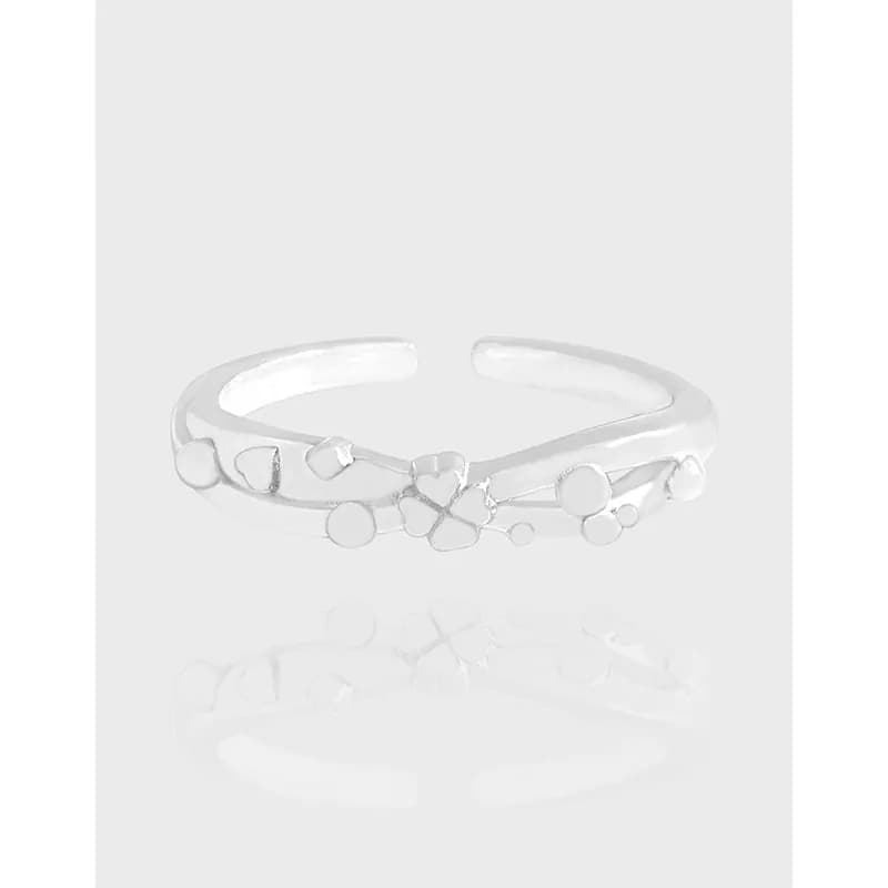 Polished sterling silver open ring with a small floral charm and circular bead accents along the band.