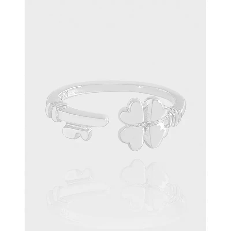Polished sterling silver ring with a four-petal clover motif on an open cuff band.